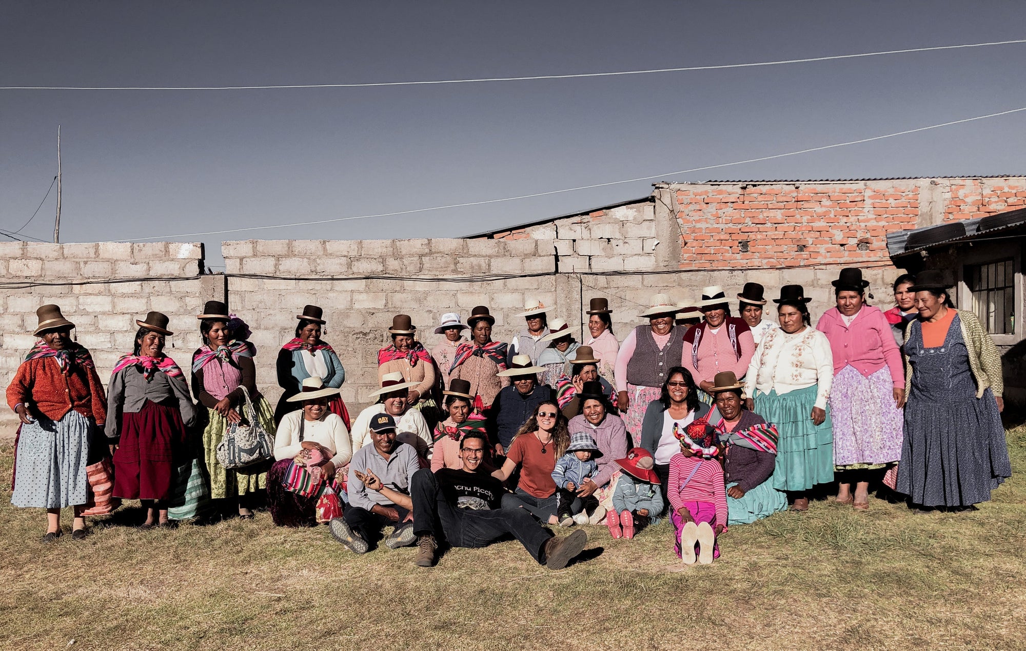 Group of women in traditional Andean clothing posing outdoors in a knitting community
