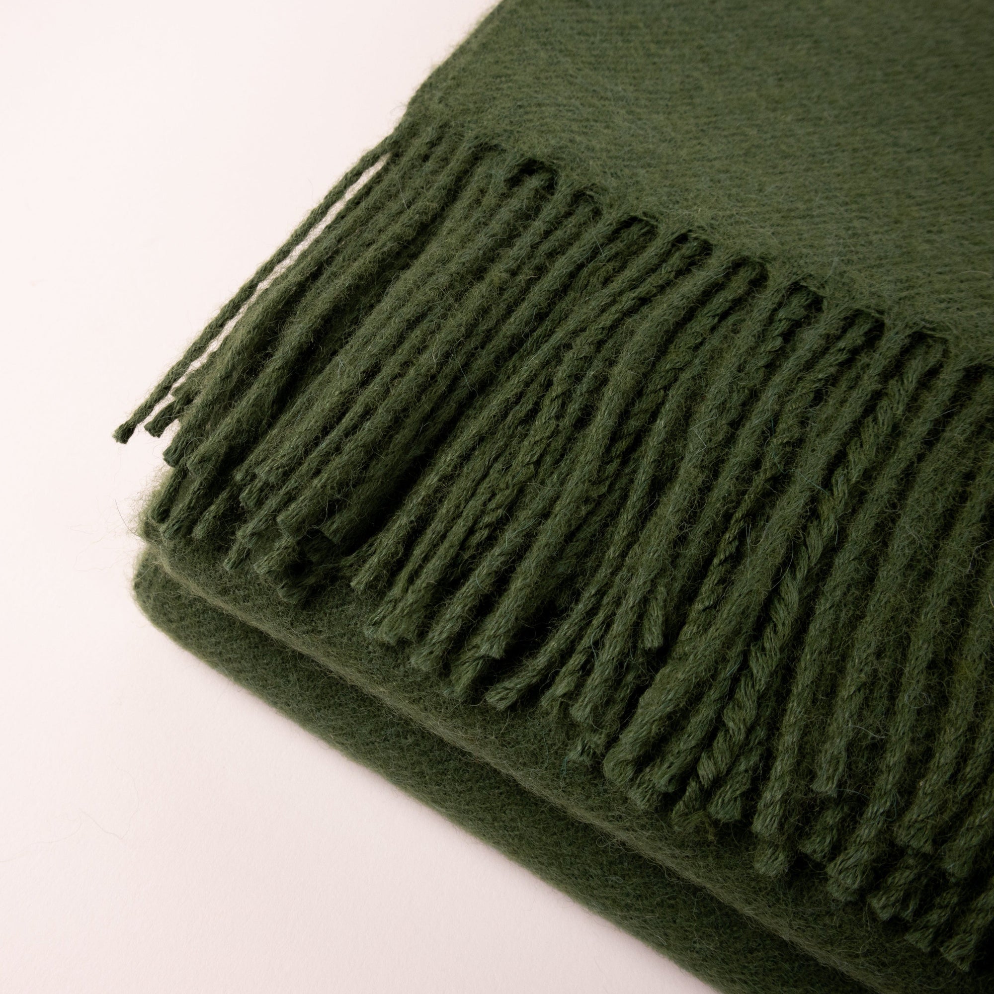 Cozy bedroom with green alpaca throw blanket on bed, textured pillows, and warm decor accents.