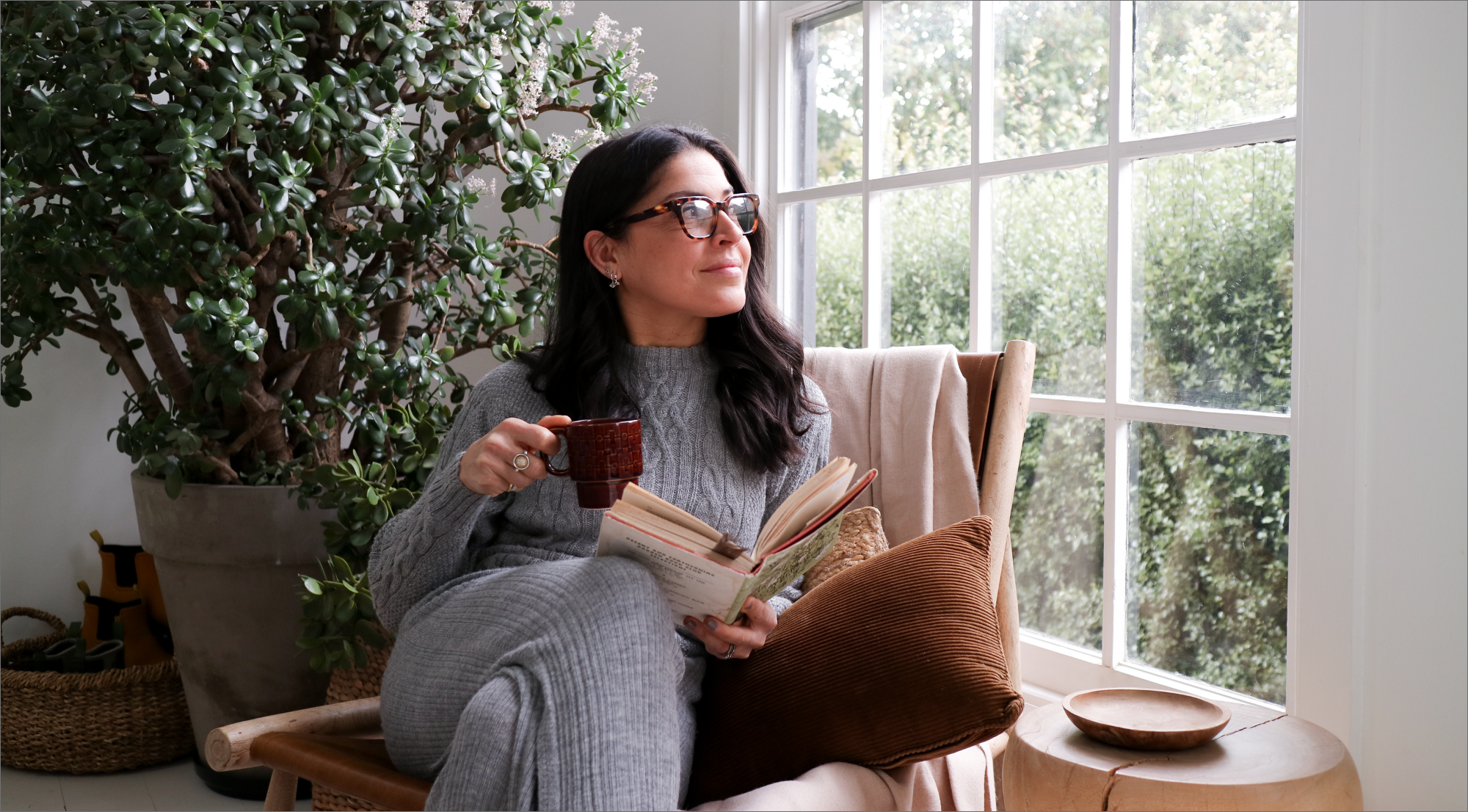 Smiling woman relaxing on cozy fur rug with slippers, blanket, and mug for Mother's Day gift guide