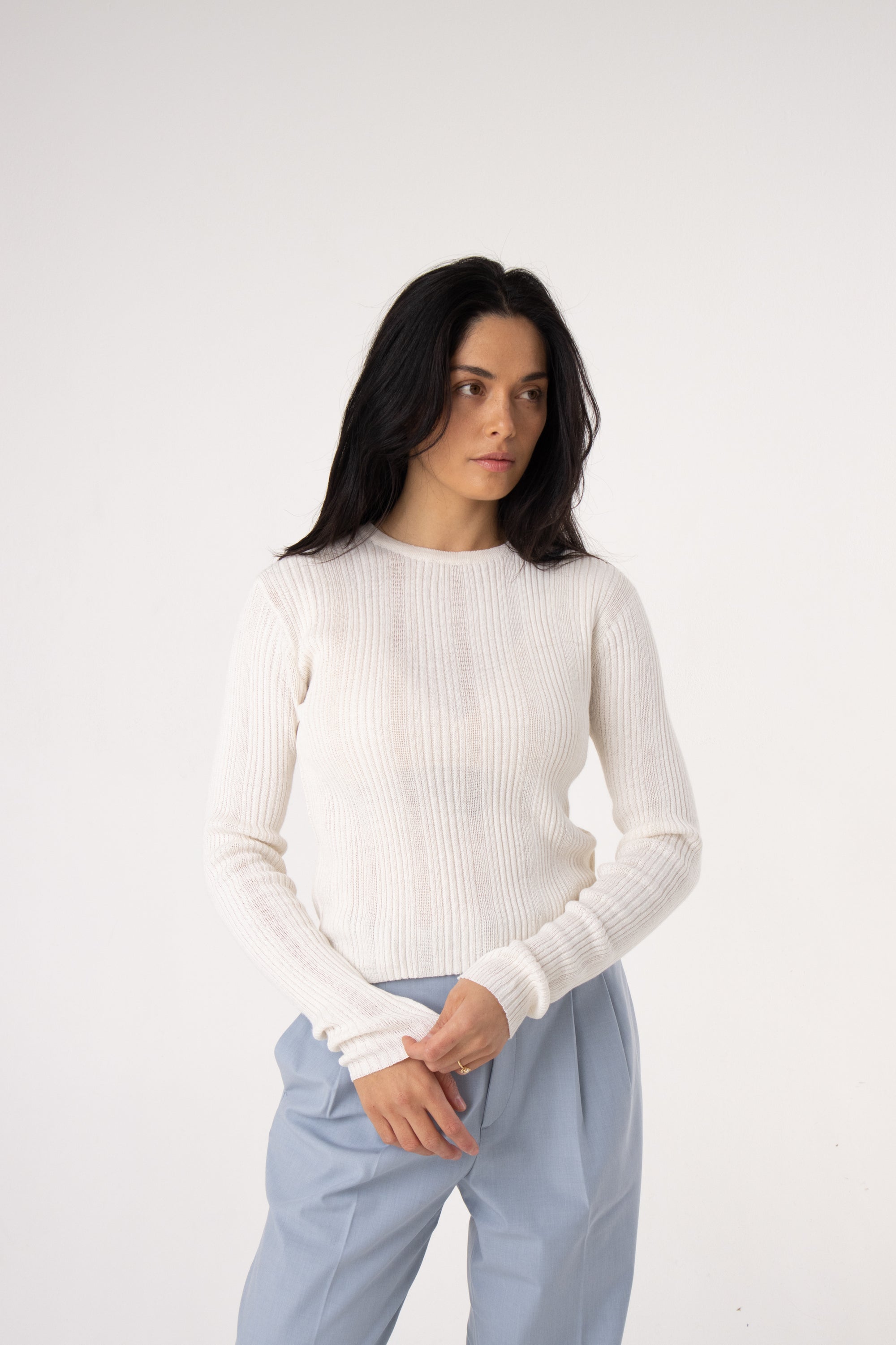 Woman wearing white ribbed knit long sleeve top and light blue trousers