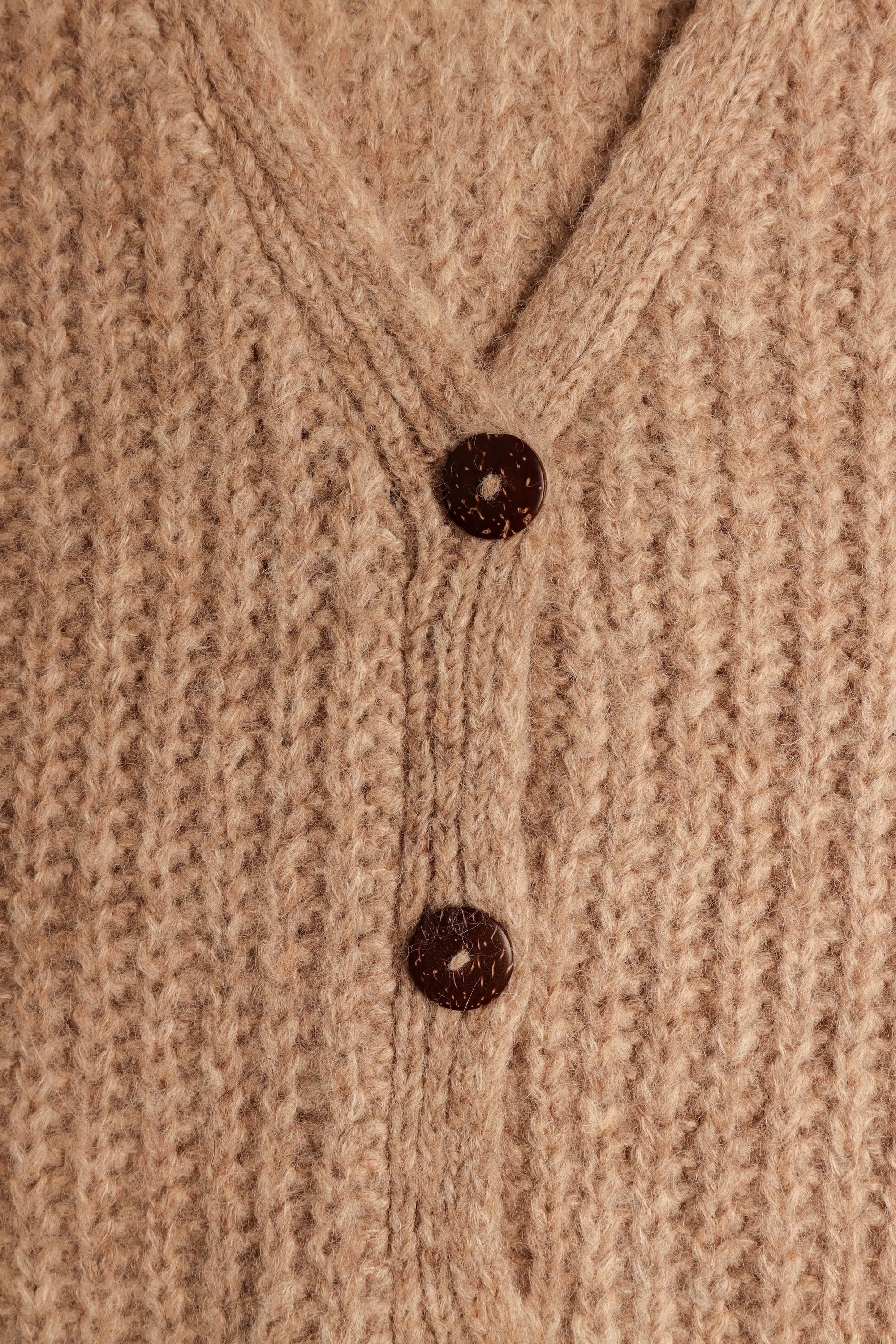 Woman wearing a cozy gray knit cardigan over a cream turtleneck and trousers